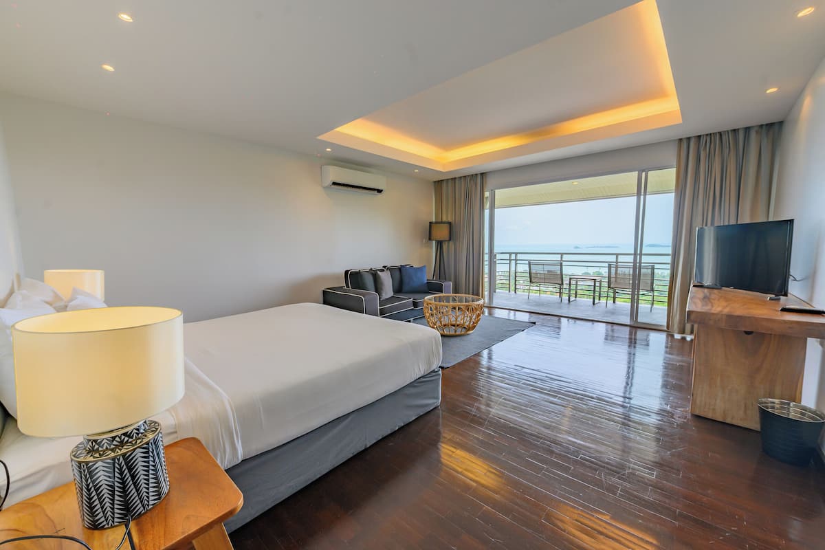 Una habitación de hotel moderna con una cama grande, un escritorio, un televisor y un balcón con vistas.