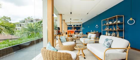 Una sala de estar moderna con muebles de mimbre, un sofá blanco y una pared de acento azul.