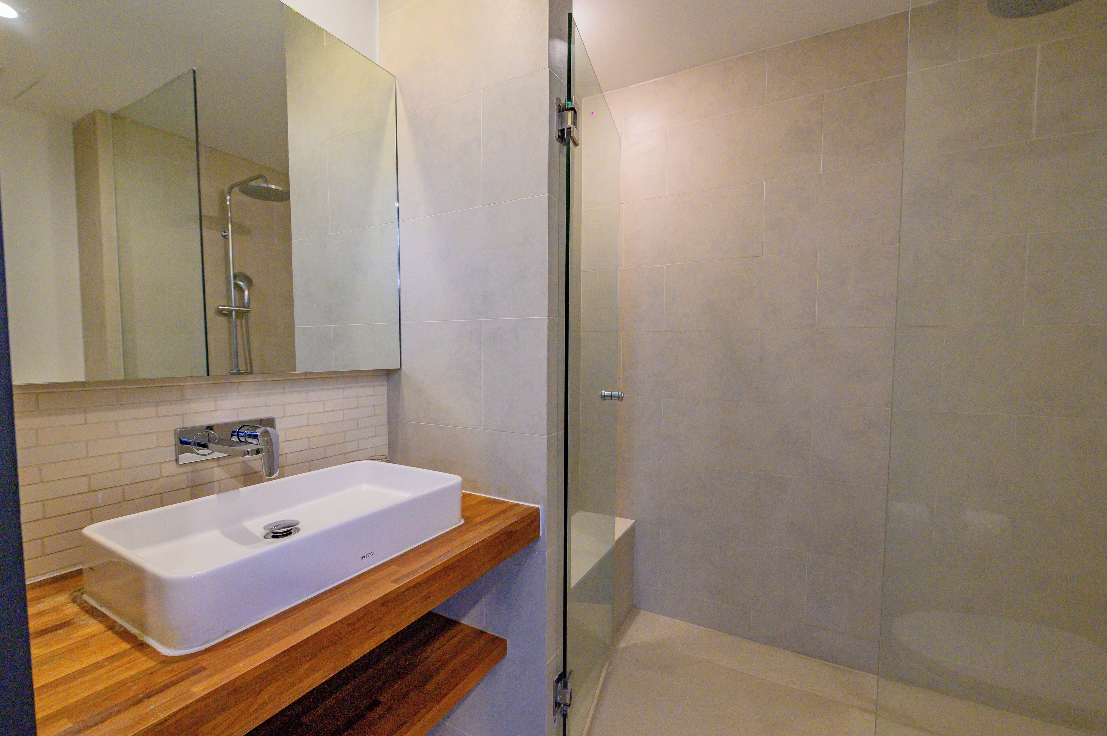 A modern bathroom with a white sink, wooden countertop, and a glass shower enclosure.