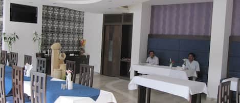 A modern dining area with a long table, chairs, and a counter.