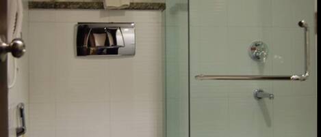 A bathroom with a glass-enclosed shower, a toilet, a towel rack, and a hand dryer.