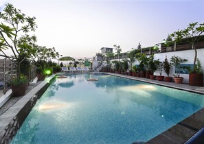 A swimming pool with tiled edges, surrounded by potted plants and a metal railing. - Hotel Taj Resorts (Agra)