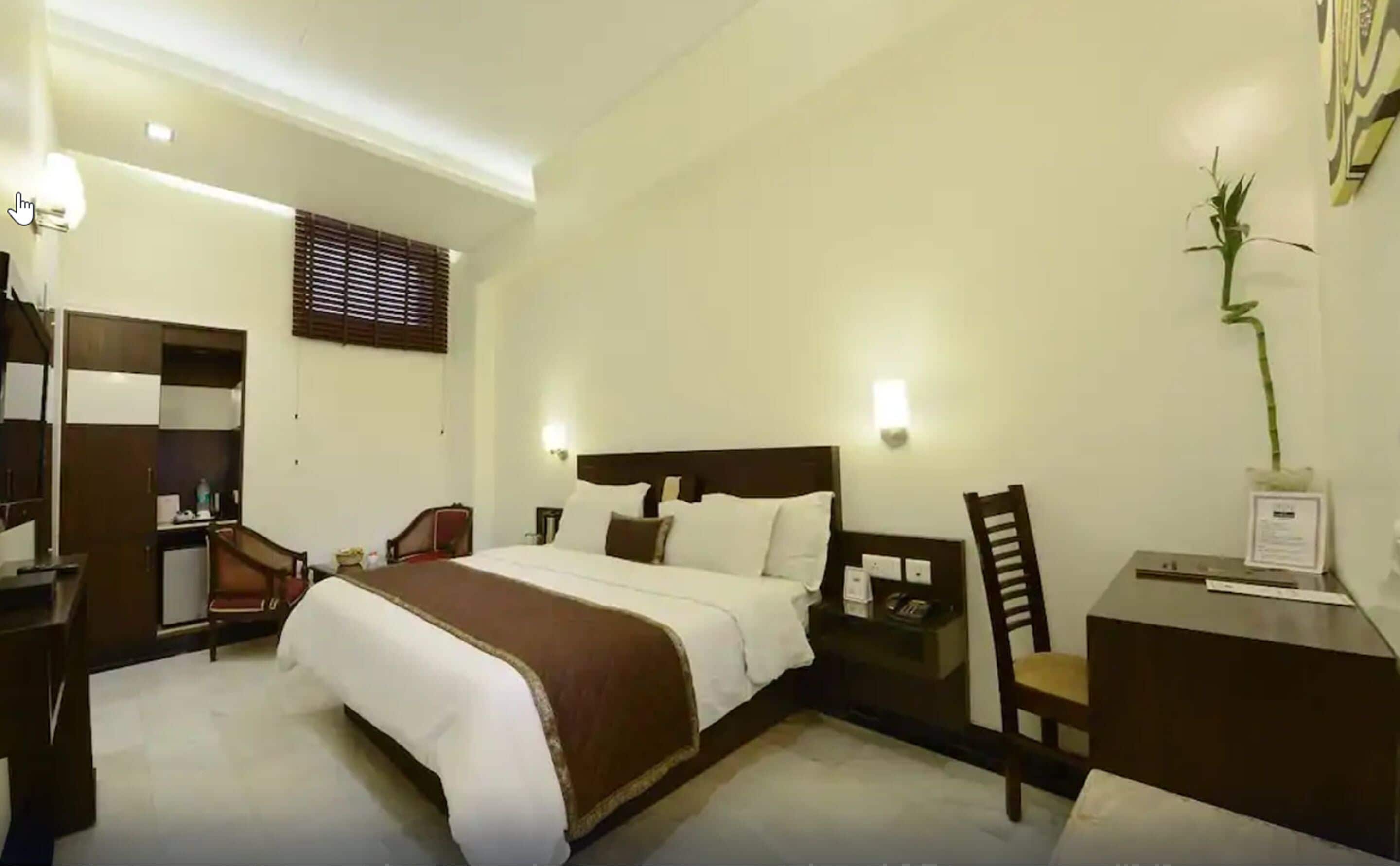 Een hotelkamer met een groot bed, een bureau met stoel, een kledingkast en een nachtkastje.
