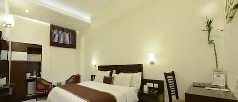 Una habitación de hotel con una cama grande, un escritorio con silla, un armario y una mesita de noche.