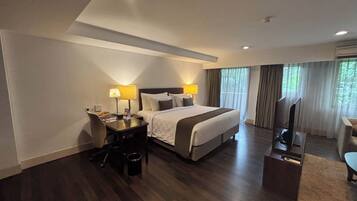 A hotel room with a bed, desk, chair, and a television.