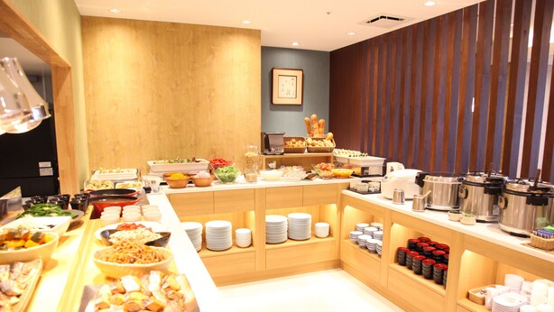 A buffet setup with various food items and beverages, wooden counters, and a modern interior design.