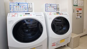 Two front-loading washing machines with control panels, user manuals, and a 'Take Out Menu' sign on the wall.