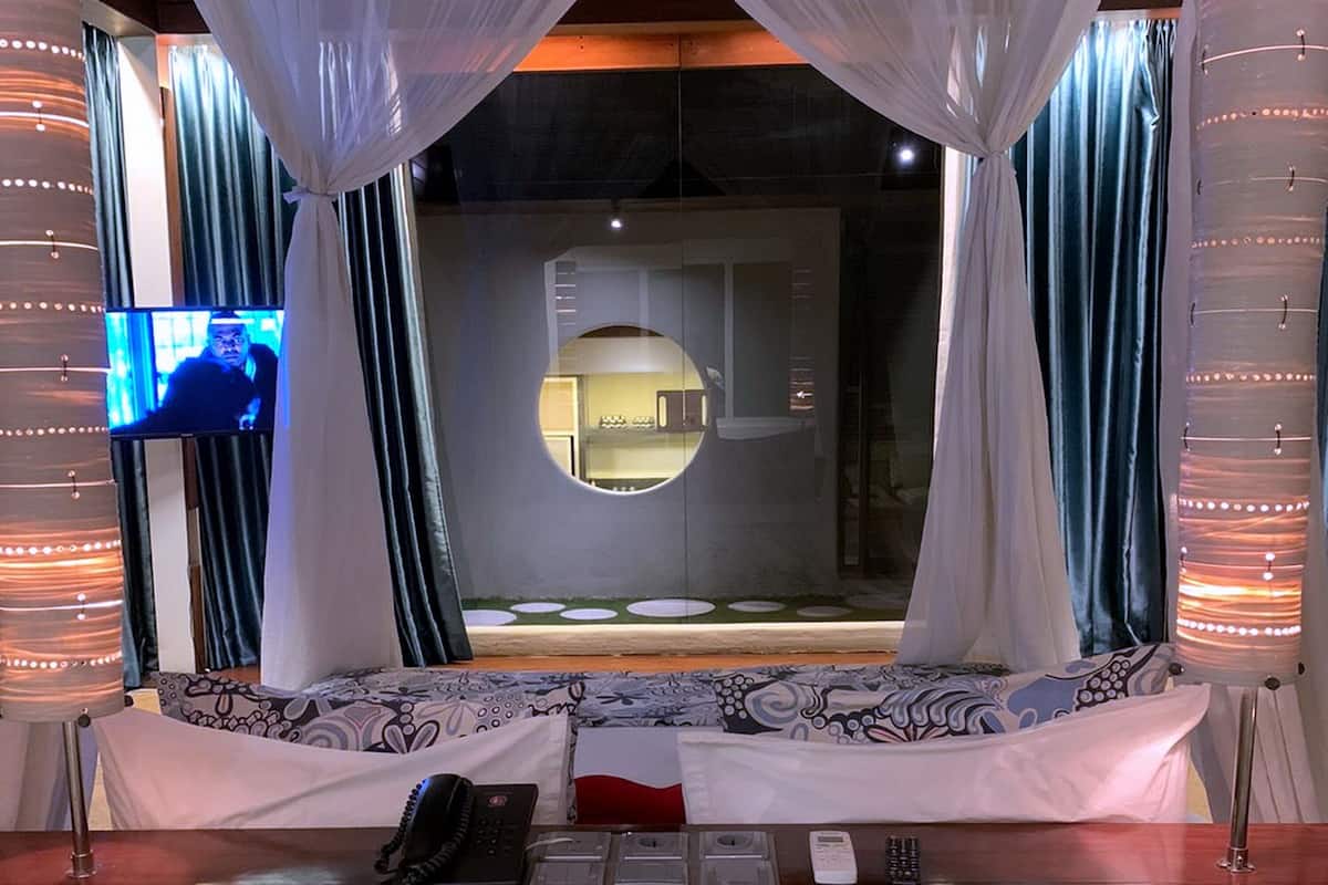 A room with a bed, a TV, and a circular mirror.