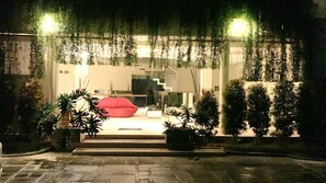 A modern building with a glass facade, a red bean bag chair, and potted plants. - Kiss Villas Bali (Seminyak)