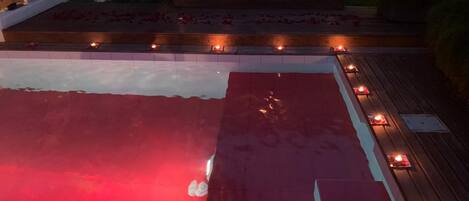 An outdoor pool area with lounge chairs and a wooden deck.