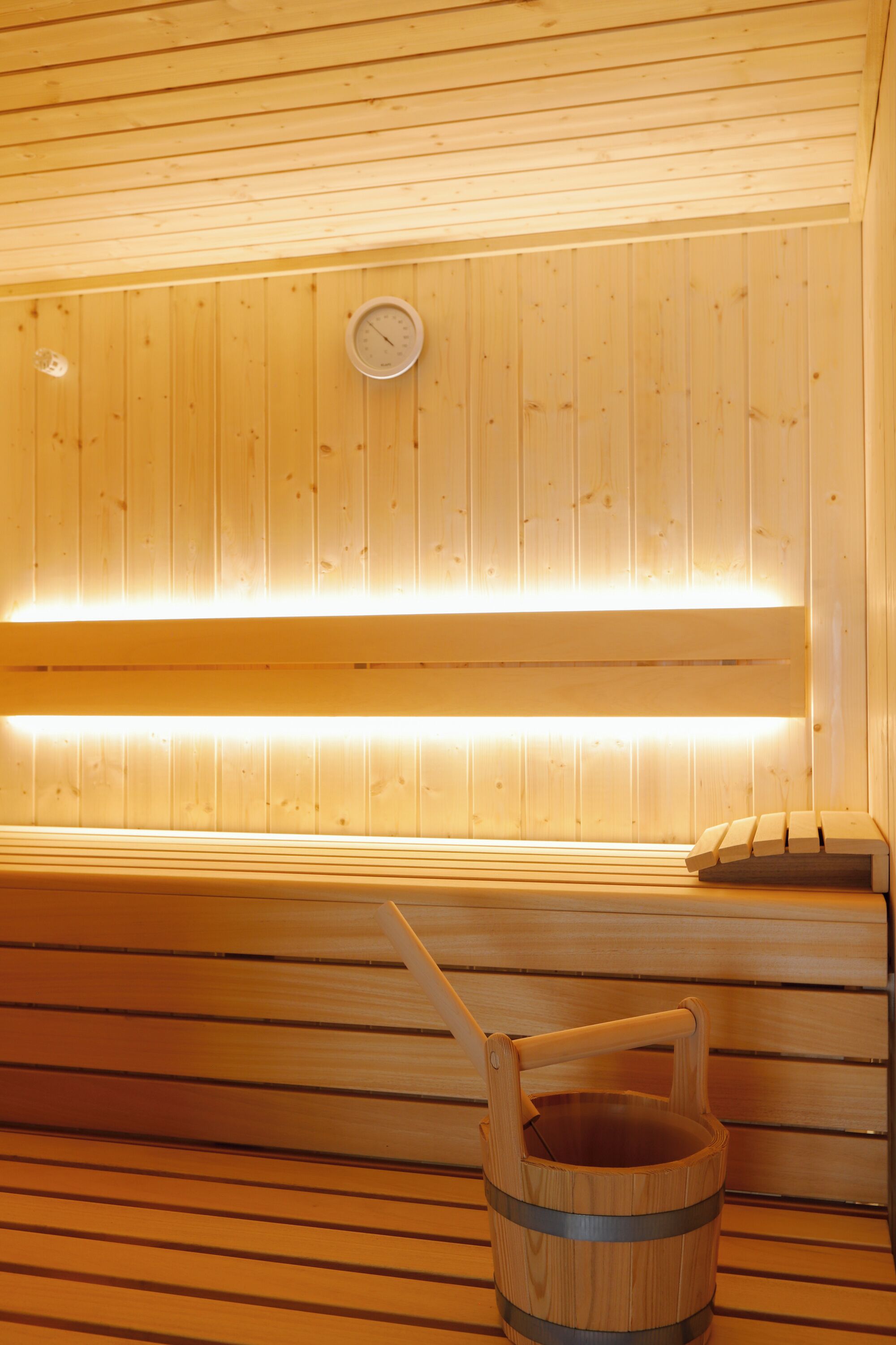 A wooden sauna with a bench and a wooden bucket.