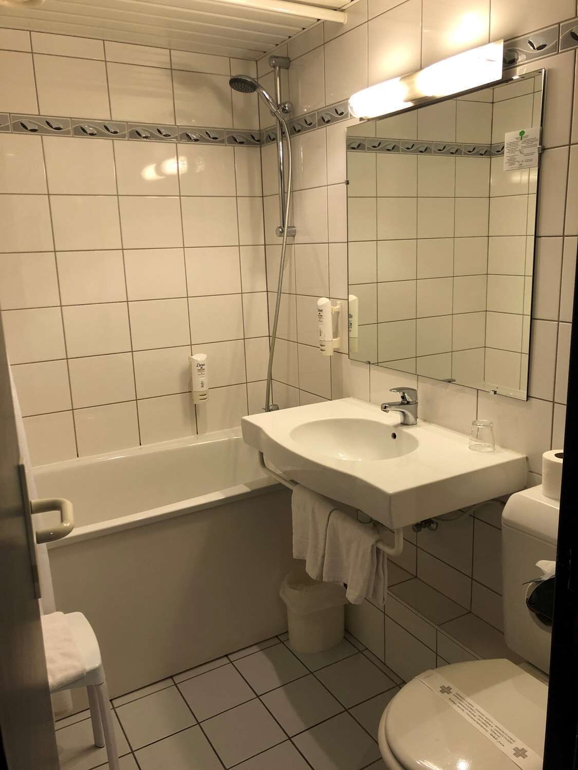 A bathroom with a bathtub, a sink, a toilet, and a mirror.