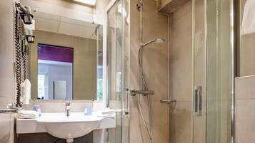 Un baño moderno con ducha de vidrio, un lavamanos blanco y un inodoro.