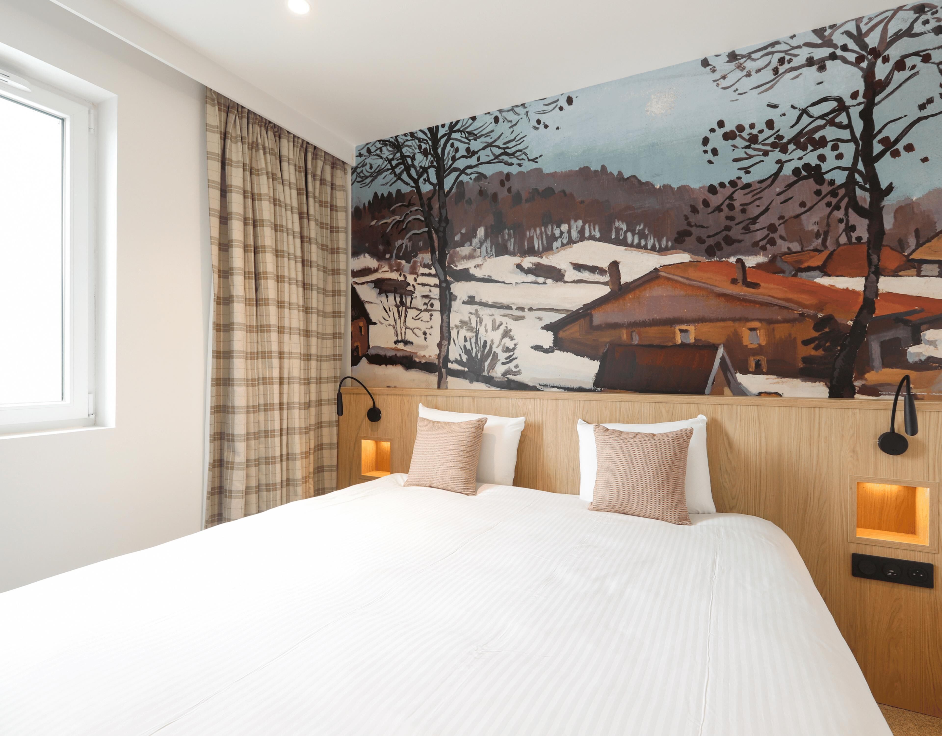A bedroom with a bed, a painting of a snowy landscape, and a window with curtains.