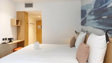A modern hotel room with a large bed, a desk with a chair, a painting on the wall, and a door leading to another room.