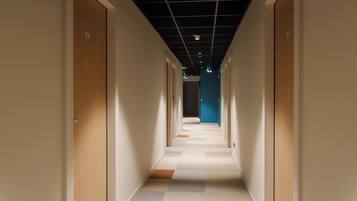 A corridor with doors on both sides, a checkered floor, and a blue wall at the end.