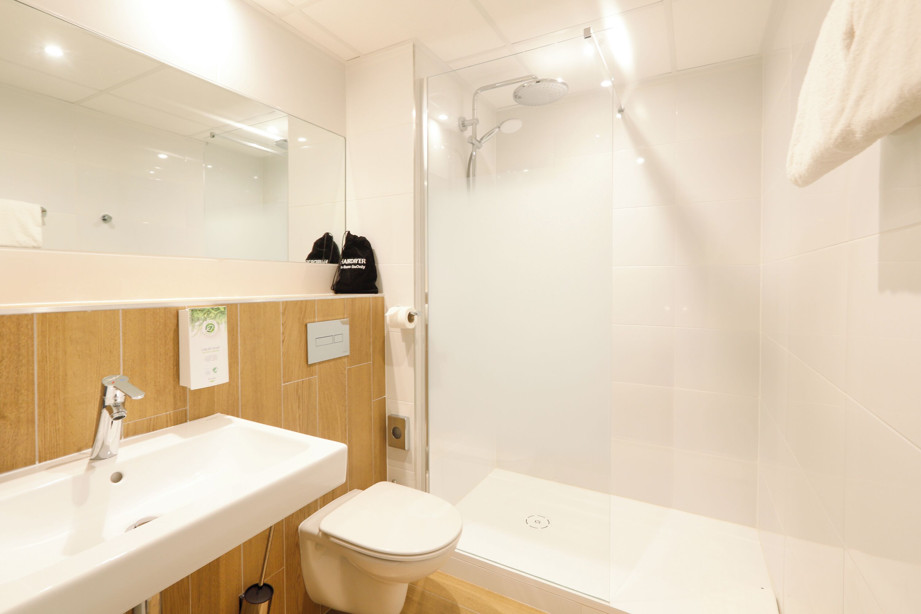Un baño moderno con lavamanos, inodoro y ducha con mampara de vidrio.