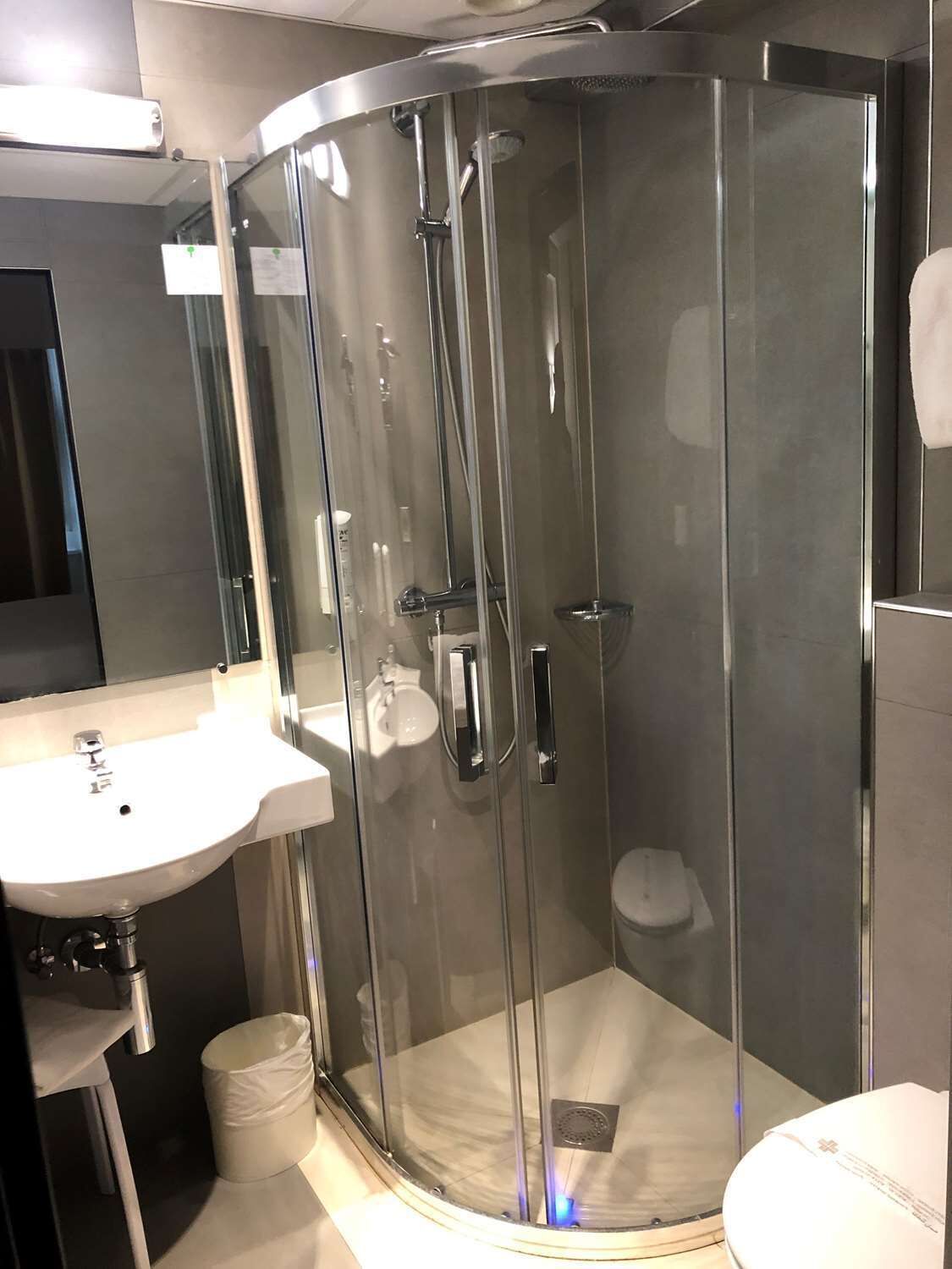 A modern bathroom with a glass-enclosed shower, a white sink, and a toilet.