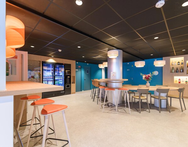 Un área de bar moderna con taburetes altos, una barra y un refrigerador con productos.