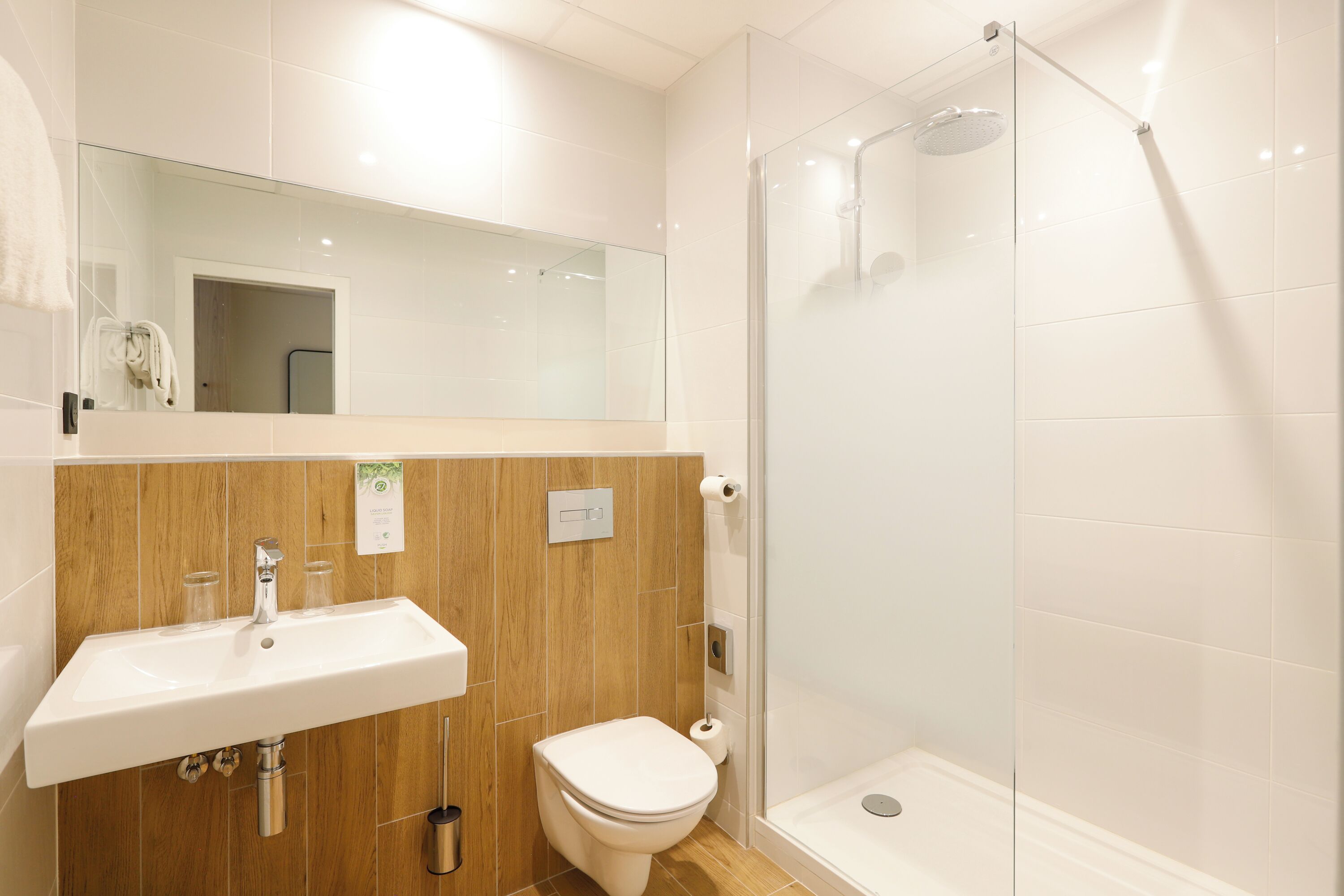 A modern bathroom with a glass-enclosed shower, a sink, and a toilet.