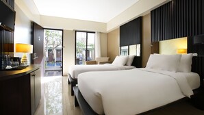A hotel room with two beds, a desk with a lamp, and a TV. - Hotel Santika Kuta Bali (Kuta)