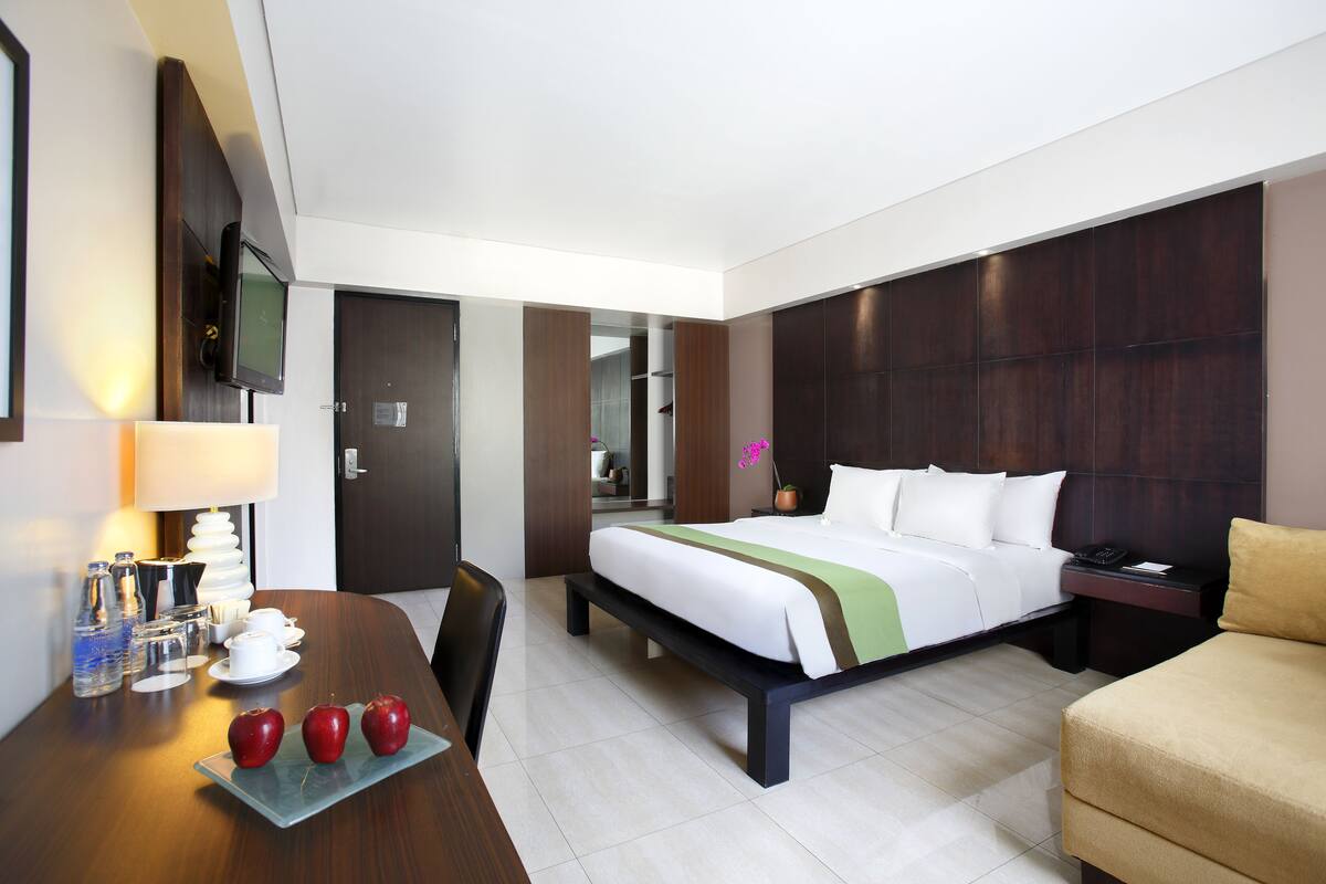 A hotel room with a bed, bedside table, desk, and chair.