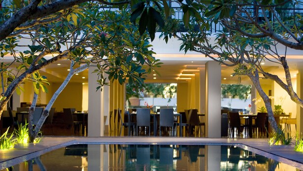 An indoor pool area with a dining area and seating. - Hotel Santika Kuta Bali (Kuta)