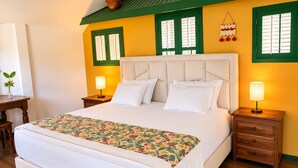 A bedroom with a bed, two nightstands, a wooden floor, and green-framed windows. - Rancho El Sobrino (Sabana Westpunt)