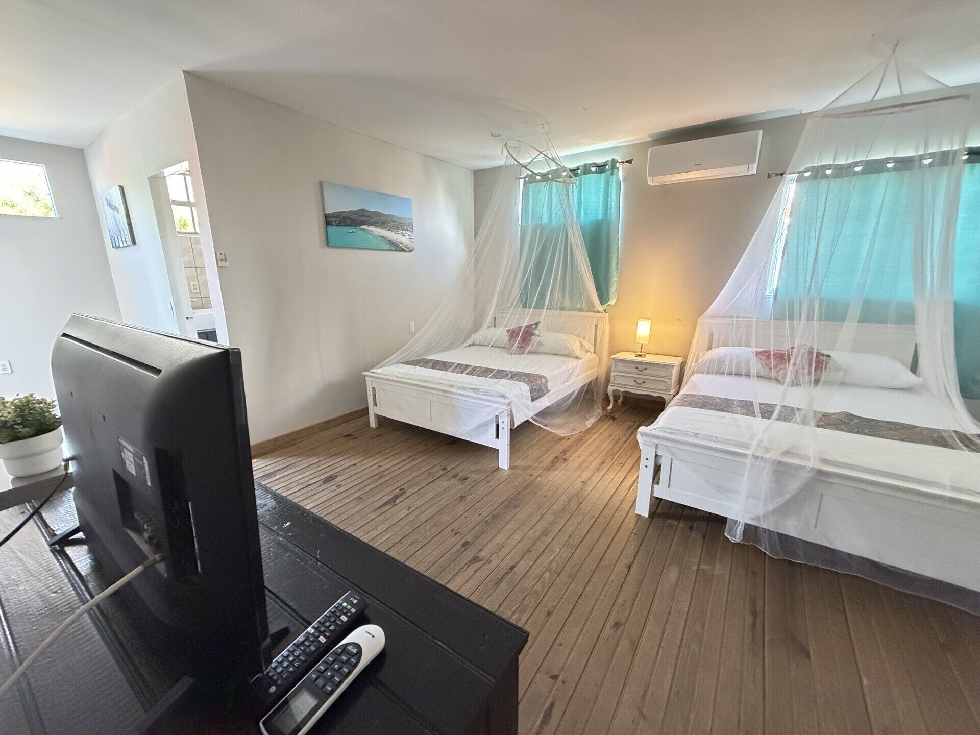 Una habitación con dos camas, un televisor y un control remoto.