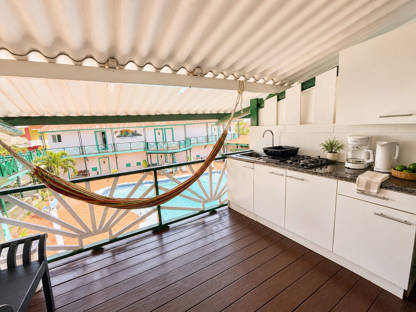 A kitchen with a hanging hammock, a pool, and a view of buildings.