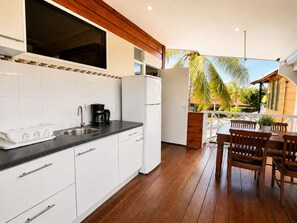 A modern kitchen with white cabinets, a black countertop, and a wooden dining area with a table and chairs. - Rancho El Sobrino (Sabana Westpunt)
