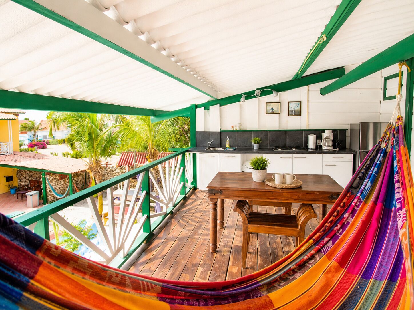 A covered outdoor area with a wooden table, chairs, and a hammock.