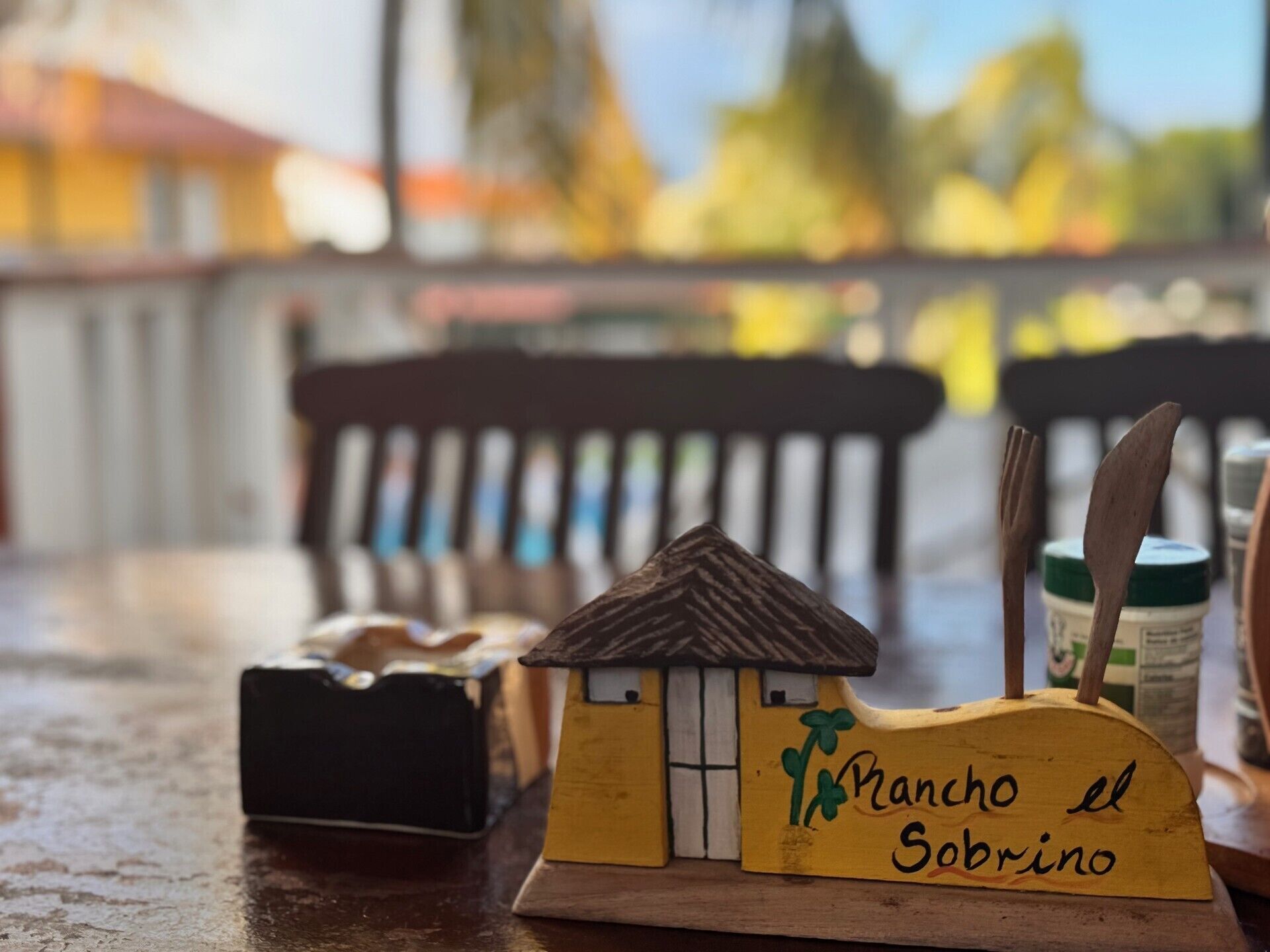 A small wooden model of a house with the text 'Pancho el Sobrino' on it, placed on a table with a blurred background.