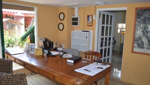 A spacious room with a large wooden table, two clocks on the wall, and a door leading to another room. - Rancho El Sobrino (Sabana Westpunt)