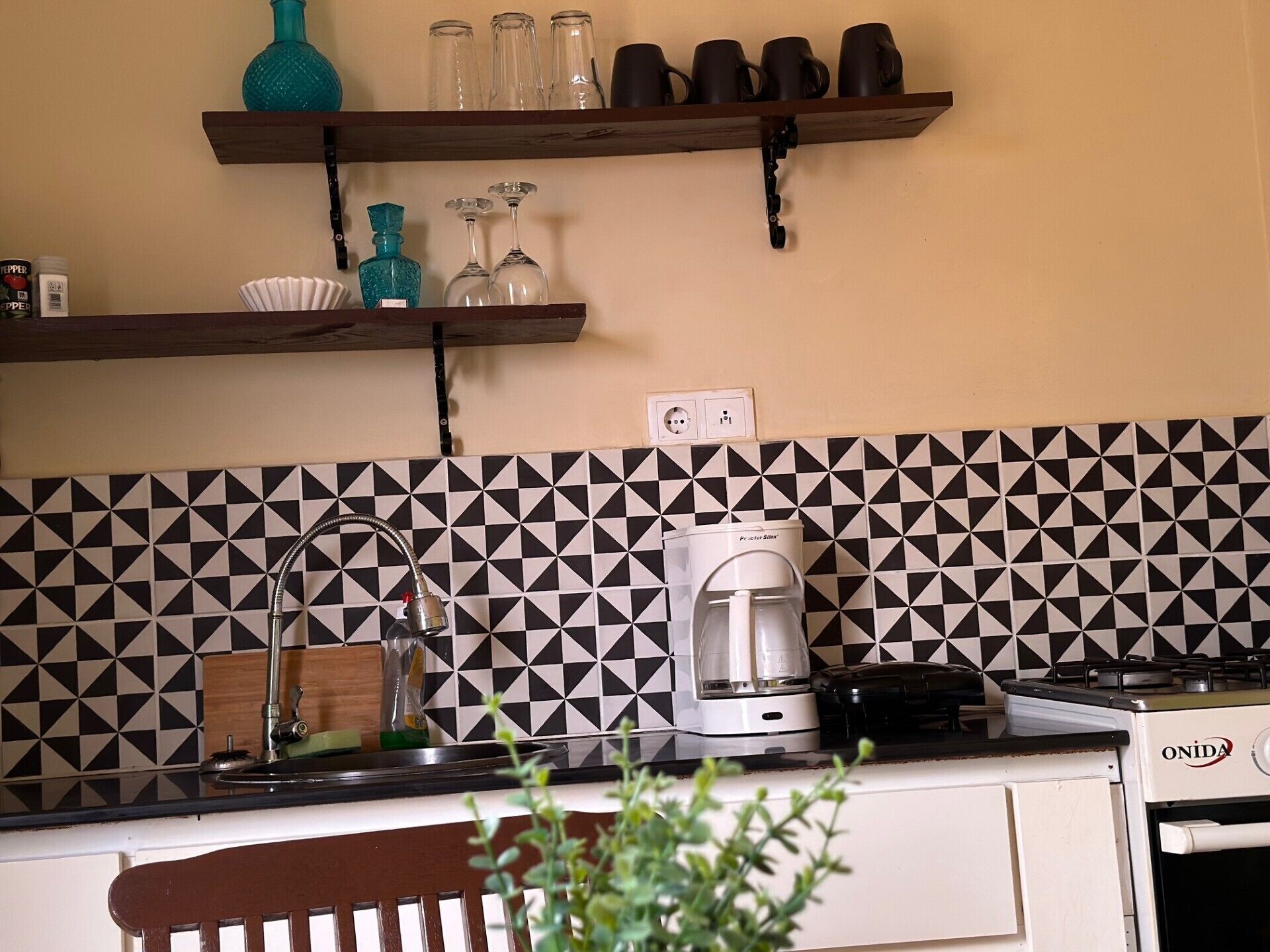 A kitchen with a coffee maker, a stove, and a sink.