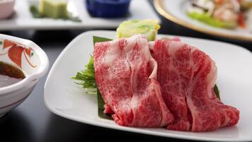 Un tavolo da pranzo con diversi piatti, tra cui un piatto di carne cruda, una ciotola di zuppa e una piccola ciotola blu.