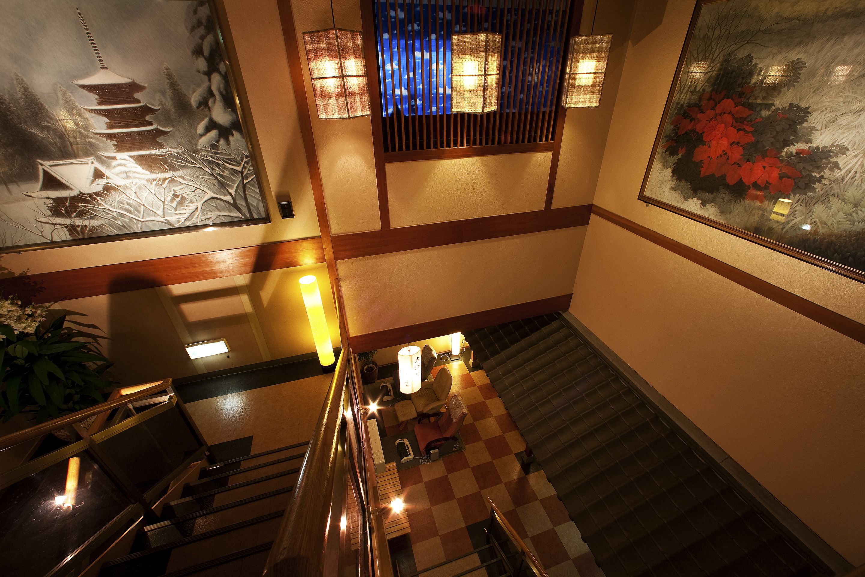 A staircase with a checkered floor, a wooden railing, and a seating area with chairs and a table.