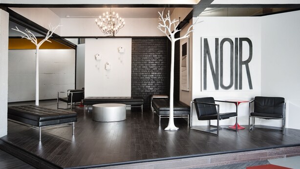 A modern interior with a dark wood floor, black leather seating, a white tree sculpture, and a chandelier. - ZUM Auberge d'été - Résidences de l'Université de Montréal (Montreal)