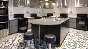 A modern kitchen with stainless steel appliances, a central island with stools, pendant lighting, and patterned flooring. - ZUM Auberge d'été - Résidences de l'Université de Montréal (Montreal)