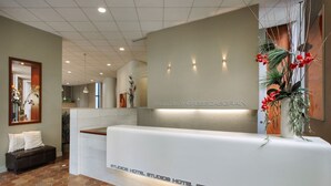 A reception desk with a modern design, a bench, and a potted plant with red flowers. - ZUM Auberge d'été - Résidences de l'Université de Montréal (Montreal)