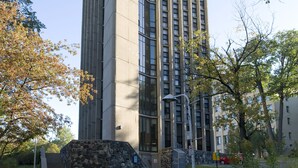 A tall, modern building with a rectangular base and a narrow top, surrounded by trees and a clear sky. - ZUM Auberge d'été - Résidences de l'Université de Montréal (Montreal)