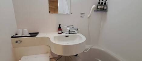 Une salle de bain avec un lavabo blanc, des toilettes, un miroir et une douche.
