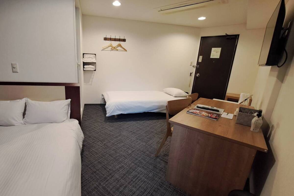 Une chambre d’hôtel avec deux lits, un bureau et un miroir.