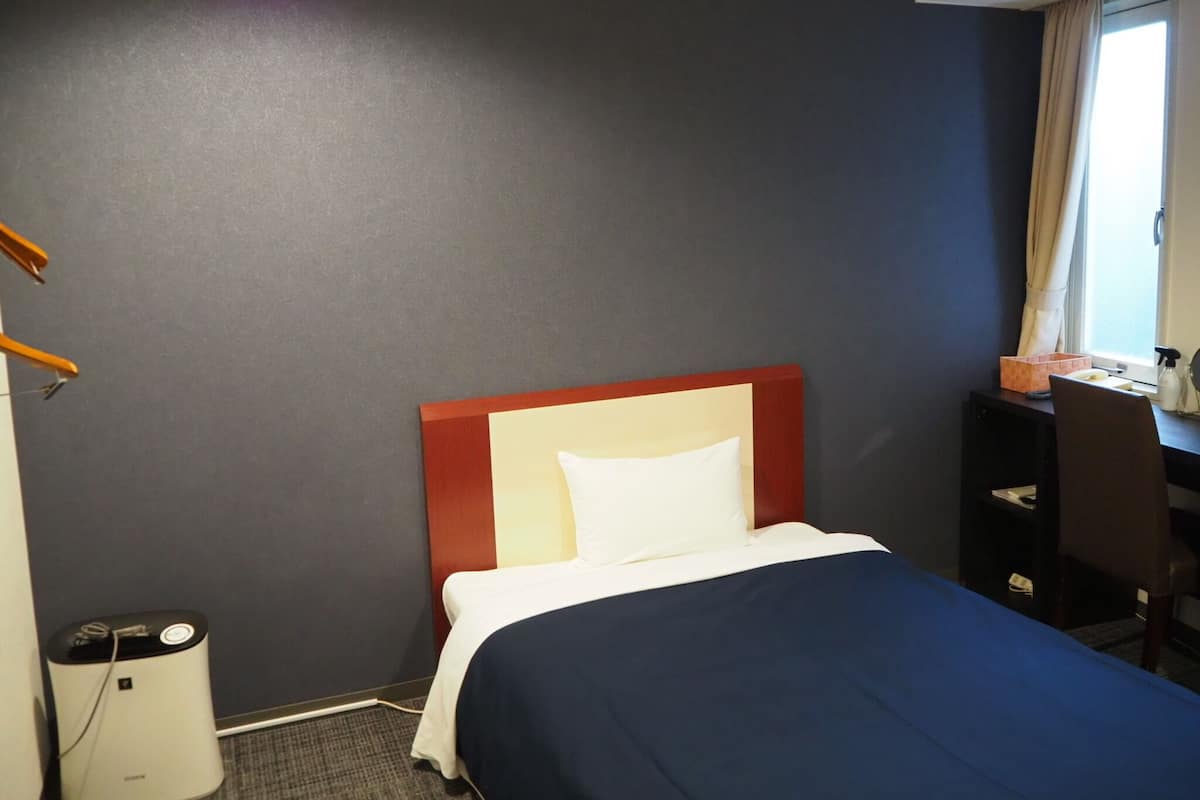 Une chambre d’hôtel avec un lit, un bureau et une chaise.