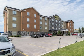 A multi-story hotel with a stone facade and a parking lot with several cars. - MainStay Suites Winnipeg Airport (Winnipeg)