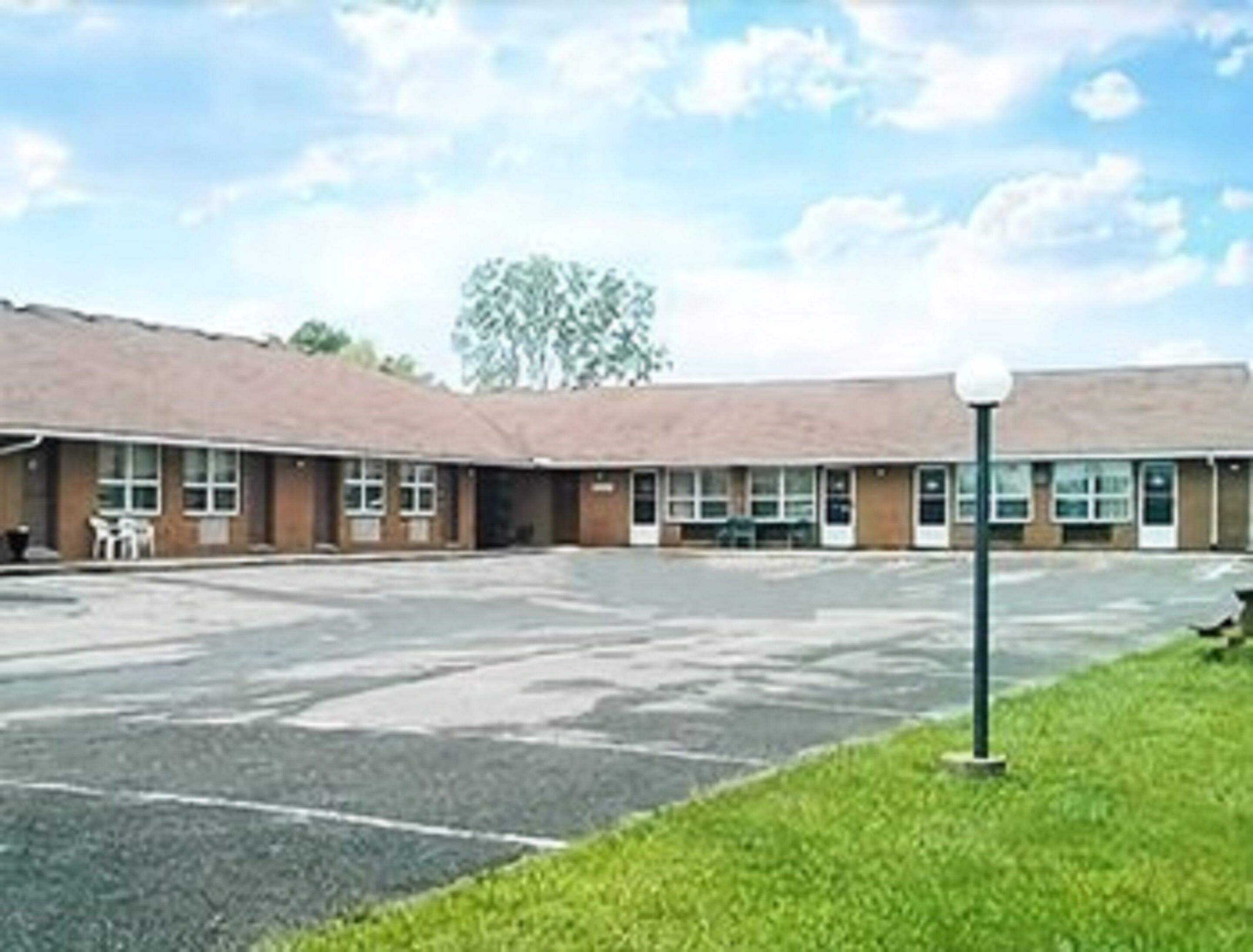 A motel with a parking lot and a grassy area.
