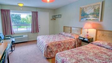 A hotel room with two beds, a desk, a chair, a lamp, and a painting on the wall.