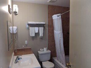 A bathroom with a sink, toilet, and shower. There are towels hanging on a rack and a glass shower door.