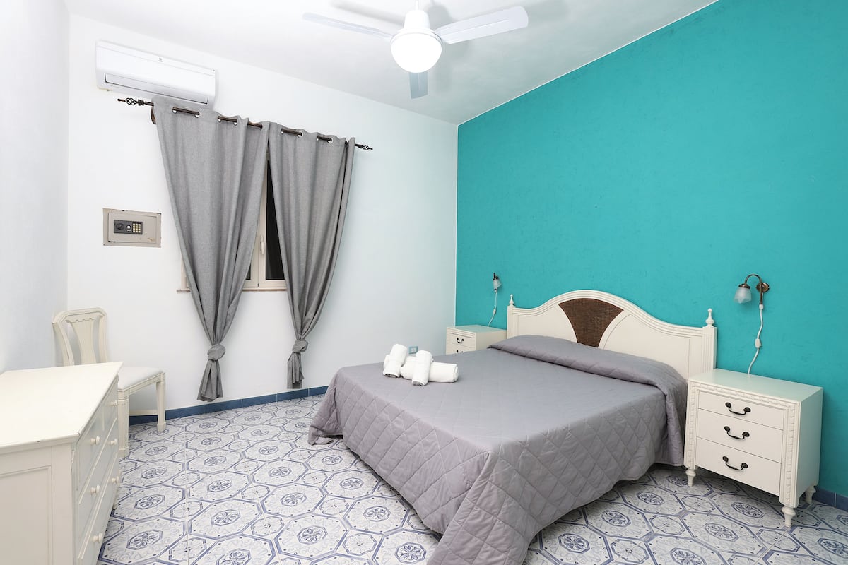 A bedroom with a bed, bedside tables, a chair, and a desk.