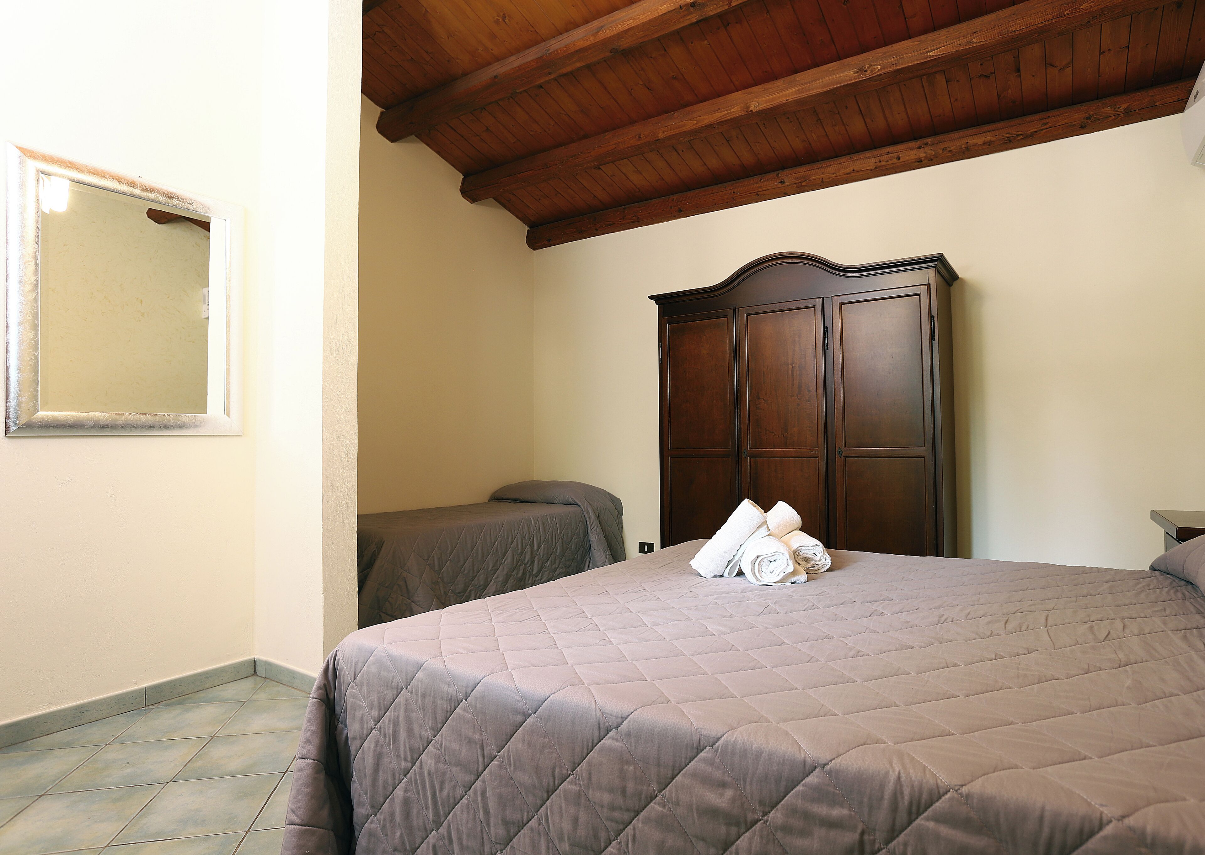 Un dormitorio con una cama grande, un armario de madera y un espejo en la pared.
